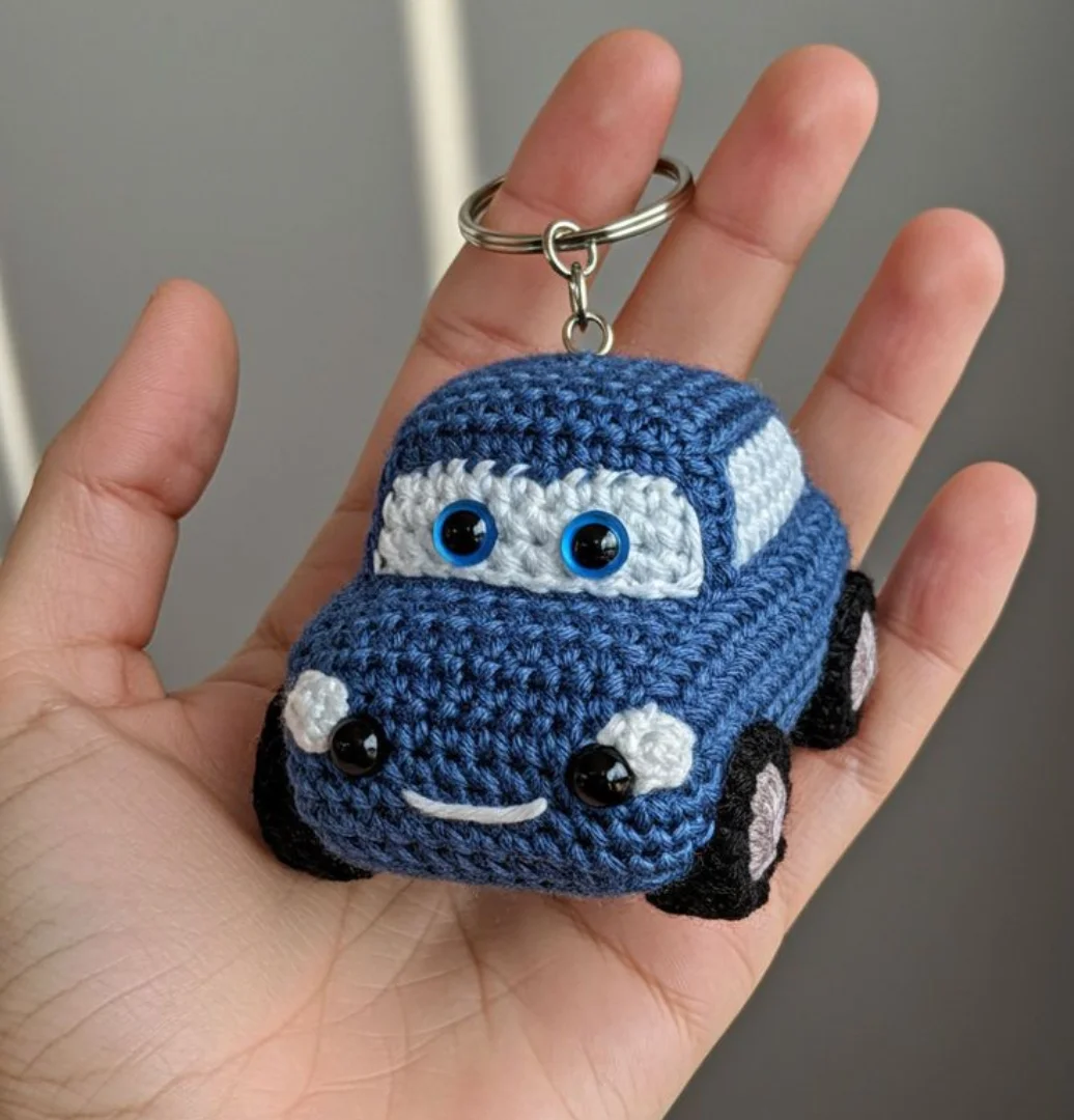 Handmade blue crochet car keychain resting on an open hand